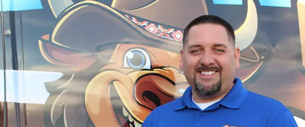 Vaquero Plumbing's owner in front of the company's branded service van