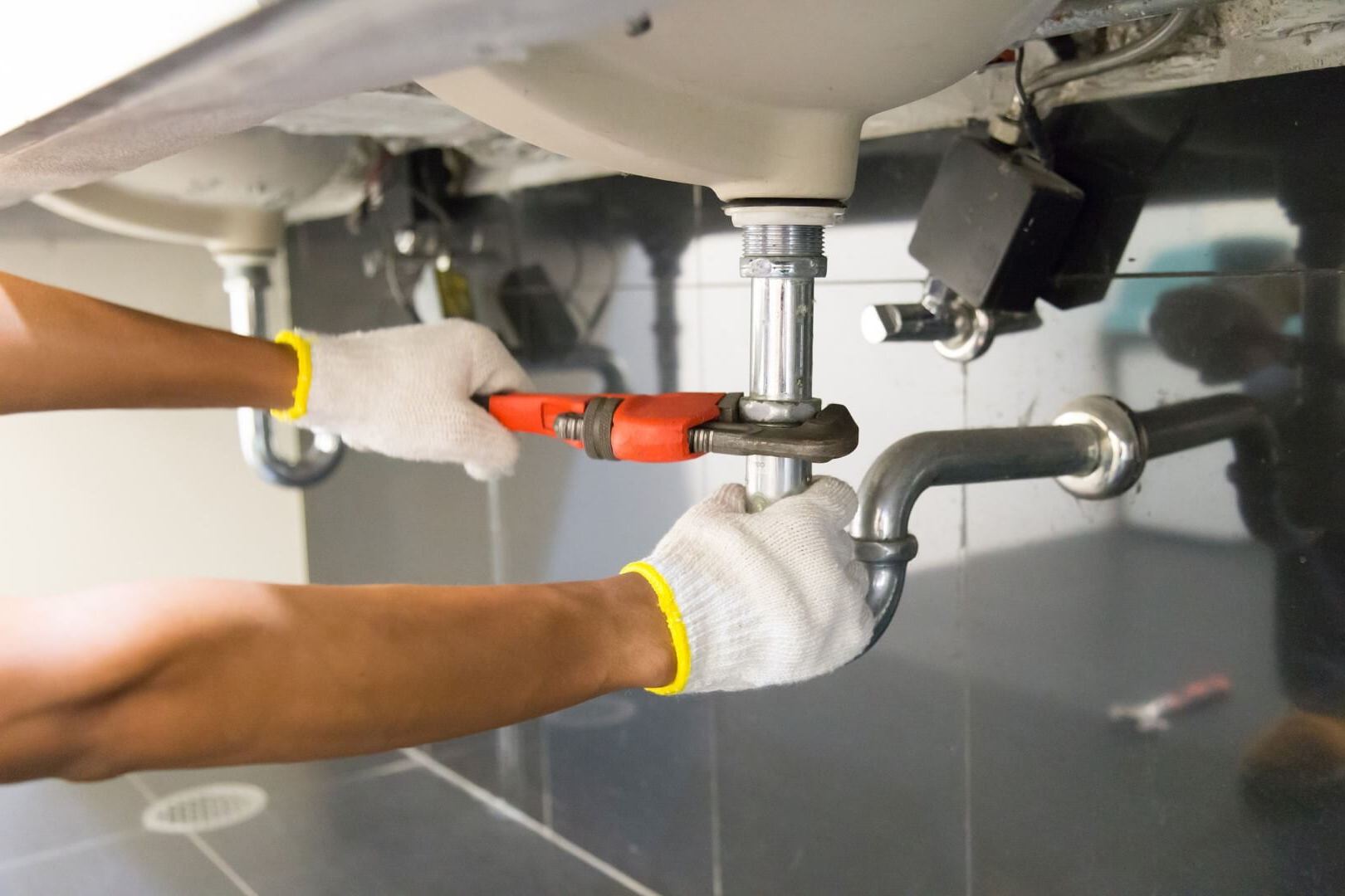 Plumber fitting new supply lines under a sink